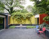 Outdoor, Stone Patio, Porch, Deck, Garden, and Small Patio, Porch, Deck Vines spill over primary-colored, glazed-brick walls, which recall Girard’s eye-popping graphics.  Photos from This Michigan Couple Found Out They Own the Last Standing Home by Alexander Girard