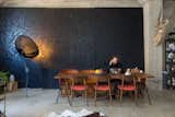 Dining Room, Concrete Floor, Table, Chair, and Floor Lighting Rather than treating the concrete walls, Morrison hung a massive painting by her brother to give the dining room depth.  Photo 8 of 18 in Art by Anna McCollister from Budget Breakdown: A Bay Area Warehouse Becomes a Live/Work Space for $124K