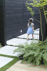 Outdoor, Wood, Horizontal, Concrete, Side Yard, Trees, and Shrubs Hana Bea, 6, follows the concrete pavers that lead from the front yard to the side entrance.  Outdoor Side Yard Concrete Horizontal Wood Trees Photos from A Low-Key Landscape Gives a  Vancouver Family a New Lease on Outdoor Living
