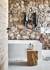 Scott incorporated rough stones excavated on the property into the bathrooms, creating a contrast with the clean lines of the rest of the house. The tub is custom.