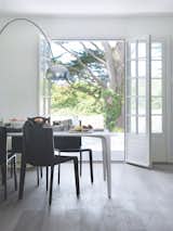 Dining Room, Table, Floor Lighting, Light Hardwood Floor, and Chair The dining area is just steps from the outdoors. A B&amp;B Italia dining table and chairs create a minimalist setting.  Photo 7 of 12 in A Stone Retreat in France Gets a Sleek Glass Addition