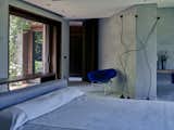 The master bedroom features a bed by Antonio Citterio, Papiro floor lamps by Sergio Calatroni, and a Diamond chair by Harry Bertoia for Knoll.  Photo 4 of 23 in An Architect Unites Three Brutalist Villas He Designed on Sardinia in the 1970s
