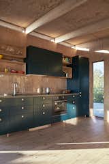 Kitchen, Colorful Cabinet, Range, Drop In Sink, Wood Backsplashe, and Light Hardwood Floor  Photo 14 of 15 in A Pint-Sized, No-Frills Summerhouse Rises From the Rocks on a Swedish Island