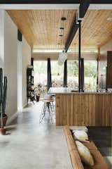 Western red cedar slat panels are paired with a pine ceiling and stained oak cabinets in the kitchen. Model Six Stools by Jeff Covey for Herman Miller line the concrete counter.