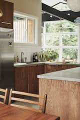 Kitchen, Ceramic Tile, Concrete, Wood, Refrigerator, Concrete, and Drop In White subway tiles and a large window over the sink brighten the kitchen.  Kitchen Concrete Wood Concrete Ceramic Tile Photos from A Self-Taught Designer Builds a Midcentury-Inspired Home on a Budget