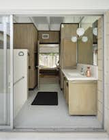 Bath Room and Ceiling Lighting The master bathroom in this Gene Leedy-designed home in Florida is mostly original, with new grasscloth paper covering the formerly white walls. The midcentury modern bathroom vanity features muted wood and white tiles for a clean, modest look.  Photo 19 of 25 in 25 Best Modern Bathroom Vanities for Your Home