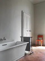 Another bathroom features a freestanding tub from Jacob Delafon in Paris. The Red Shell chair, designed by Barber &amp; Osgerby, is made of Isokon Plus’s signature material, plywood.