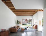 Douglas fir beams, some of which were salvaged from the original home that sat on the property, run in perpendicular lines overhead. Certain sections of the ceiling are exposed, while others are covered in drywall. For flooring, the residents, who have two young children, selected durable polished concrete. The Sven Charme sofa is by Article and the teak bureau is vintage. 