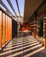 Together, the louvered sections of fence and the trellised roof overhangs paint the breezeway with shadows.