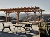 Outdoor, Large, Back Yard, Shrubs, Hanging, Wood, and Concrete A cement slab and wood deck offer space for meals and stargazing. Sam built the furniture himself.  Outdoor Concrete Hanging Back Yard Large Photos from A Tech Entrepreneur Rehabs an Off-Grid Dome Home in Joshua Tree