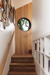 Architect Murray Barker renovated this 1,180-square-foot, two-story bungalow for Fleur Glenn at the edge of her property in the Clifton Hill suburb of Melbourne, Australia. Silvertop ash and stringybark timber form the narrow stairway to the second floor, which holds the principal bedroom and a study. "I wanted the journey to Fleur’s bedroom to feel quite different from the rest of the house," says Barker. "There are views of the trees and sky, including a round window that frames the beautiful dark bark of one of the eucalyptus trees."