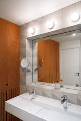 Bath Room, Wall Lighting, and Wall Mount Sink The bathroom’s cement tiles, designed by Delaunay to evoke waves and made by The Mosaic Factory, frame an inset mirror.  Photos from This Live/Work Duplex in Paris Is Full of Kid- and Cat-Friendly Details