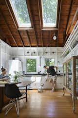 Dining, Storage, Table, Medium Hardwood, Wall, and Chair Jennifer sits at a vintage Bruno Mathsson Maria dining table in the kitchen.  Dining Wall Medium Hardwood Table Storage Chair Photos from This Lakeside Cabin in New York Is Offbeat in the Best Way