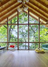 Living Room, Chair, Sofa, Pendant Lighting, and Medium Hardwood Floor Frances Bacon, the couple’s French bulldog, rests on the screened-in porch.  Studio Design LLC’s Saves from This Lakeside Cabin in New York Is Offbeat in the Best Way