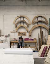 The watch installation will include display stands that resemble spruce trees, made of silicon and filled with sand and silica. An assistant unrolls foam as part of the process of creating  the trees. On the wall are semicircular frames that are used for casting round mirrors.  Photo 6 of 16 in Watch: Inside the Studio of Designer and Materials Master Fernando Mastrangelo