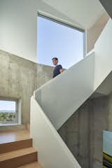 A staircase guides visitors from the home's entry in the rough cement base to the bright and airy residential space.