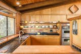Kitchen, Drop In Sink, Cooktops, Wall Oven, Tile Counter, and Ceiling Lighting Comprised of beautiful wood cabinetry and open shelving, the kitchen also has a double-oven.  Photo 3 of 15 in A Sea Ranch Stunner With a Green Roof Asks $1.3M