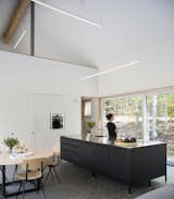 Kitchen, Wall Oven, White, Ceiling, Drop In, and Metal In the kitchen, a Vipp island holds a Gaggenau induction cooktop. The oven is by Bosch, and the hanging LED lights are from PureEdge Lighting.  Kitchen White Wall Oven Metal Photos from A House in the Catskills Hovers Over the Landscape