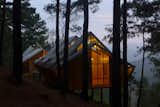 Warm lighting illuminates the cabins like lanterns. The effect is enhanced by the pitched roofs and reflections in the light wood interiors.