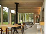 Dining Room, Table, Concrete Floor, Two-Sided Fireplace, Track Lighting, and Chair "The structure is made of a high-quality, high-strength Southern Yellow Pine, laminated and milled into beams and columns with highly-precise profiles,  Photo 6 of 12 in An Energy-Efficient Glass House in East Hampton Shifts With the Seasons