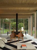 Living, Two-Sided, Chair, and Coffee Tables A slender, black double-sided fireplace distinguishes the living room from the dining area.  Living Two-Sided Photos from An Energy-Efficient Glass House in East Hampton Shifts With the Seasons