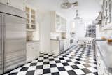 The former Manhattan home design maven Kate Spade features a sleek kitchen with white cabinets/clear fronts and checkered marble floors.