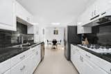 The galley kitchen features crisp white cabinetry with contrasting black accents.