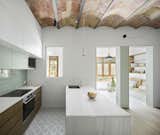 This 720-square-foot apartment in Barcelona was renovated and opened up by Nook Architects. Key to the design are the original barrel-vaulted ceilings, which are mimicked in the mixed-use gallery in the front. What was once a central hallway dividing multiple rooms—typical of older apartments—became a new common space that flows into the gallery. Materials were also limited exclusively to those already present in the space—namely, wood, ceramic, and marble. A canopy of original terra-cotta tiles line the barrel-vaulted ceilings, and a minimal aesthetic ties it all together.