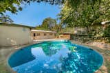 The almost 7,500-square-foot lot features a large in-ground swimming pool and a concrete patio. A separate pool house is adjacent to the main home.