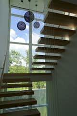 Staircase, Cable Railing, and Wood Tread "The stair tower travels vertically above the Zen garden, allowing people on the inside to look down into this beautiful space,  Photo 8 of 9 in Walls of Windows Connect a Home With Earth and Sky