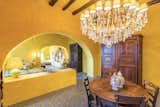 Several guest bedrooms are larger for extended stays. Here, a three-room suite painted in a golden yellow features arched openings and a plastered half wall to separate the spaces.