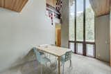 Natural light pours into the formal dining space from 18-foot-tall windows. Rising up toward the cathedral ceiling, the windows frame views of the property's many trees.  Photo 5 of 14 in This Quirky Abode Built By a Frank Lloyd Wright Apprentice Wants $575K
