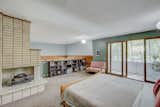The loft-like master bedroom overlooks the living room below. Rising up from the stone fireplace is a brick-faced on in the bedroom, which also offers direct access to a sunporch.  Photo 10 of 14 in This Quirky Abode Built By a Frank Lloyd Wright Apprentice Wants $575K