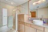 A modern master bathroom can be found off of the bedroom, complete with a large vanity and tiled shower.  Photo 12 of 14 in This Quirky Abode Built By a Frank Lloyd Wright Apprentice Wants $575K
