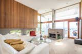 The richly textured tongue-and-groove paneling continues into the multi-leveled living room, which looks out onto views of the lake. A cozy conversation pit surrounds the fireplace hearth.