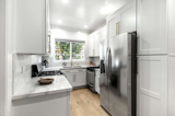 Though compact in size, the enclosed kitchen is well equipped with stainless-steel appliances, custom white cabinetry, and marble countertops.