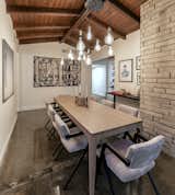 The wood-beamed ceiling continues into the dining room, which also offers an exposed brick wall. Polished concrete floors blend with the neutral color palette.