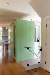 The home's main entryway, with stairs leading down to a basement. A small powder room is tucked away in a seafoam-green boxed wall, with the kitchen hidden from view behind it.