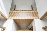 Looking from the dining area, wood cladding extends from the entryway ceiling up to railings in a second floor loft.