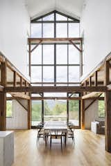 A grand space greets visitors when they first enter the home. The living room and kitchen are tucked on either side of a central dining area, which features a 35-foot-high wall of glass. Timber beams from the original barn were repurposed throughout.&nbsp;
