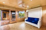 At the opposite end of the home, separated by the lanai, is the living space, which could also serve as a guest bedroom. French doors and a large picture window create an connection with the outdoors.  Photo 8 of 13 in A Breezy Prefab on Hawaii’s Big Island Lists For $379K