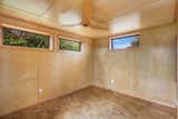 Down the hallway from the kitchen is the home's only bedroom. Clerestory windows run along both sides of the space, which is complete in Baltic Birch plywood and the same cork flooring found throughout the rest of the home.  Photo 6 of 13 in A Breezy Prefab on Hawaii’s Big Island Lists For $379K