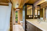 The full bathroom is adjacent to the master bedroom. A wooden ceiling accents the space, as does a large window that frames views of the natural landscaping.