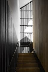 Black timber contrasts with a warm wood tone leading up the stairs.