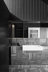 The master bathroom carries through the mix of stone and sleek black tones.  Photo 15 of 17 in This Australian Home Frames Theatrical Moments With Rough
and Shimmering Surfaces