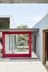 Opening to the home's main entrance on the upper level, a large red sliding door—one of three—is painted Gypsy Red by Sherwin-Williams. To the left is the kitchen and dining space, and to the right is the living room and studio.