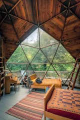 Located in a remote area of Northern California, this geodesic dome is built on an organic farm near the Pacific Ocean. It has a potbelly stove, two lofted bunks, a kitchen and dining area, and a bed beneath a dreamy geodesic window.