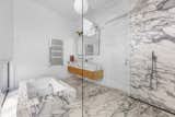 The master bathroom is clad in Arabescato marble sourced from several different Italian quarries. Sconces above the vanity were finds from eBay.
