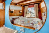 A queen bed rests on a platform at the back of the boat.