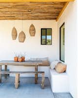 At the rear of the home, a covered dining space also features saguaro-rib ceilings and plaster bench seats.  Pendants and throw pillows sourced from markets in Mexico and Marrakech adorn the area.